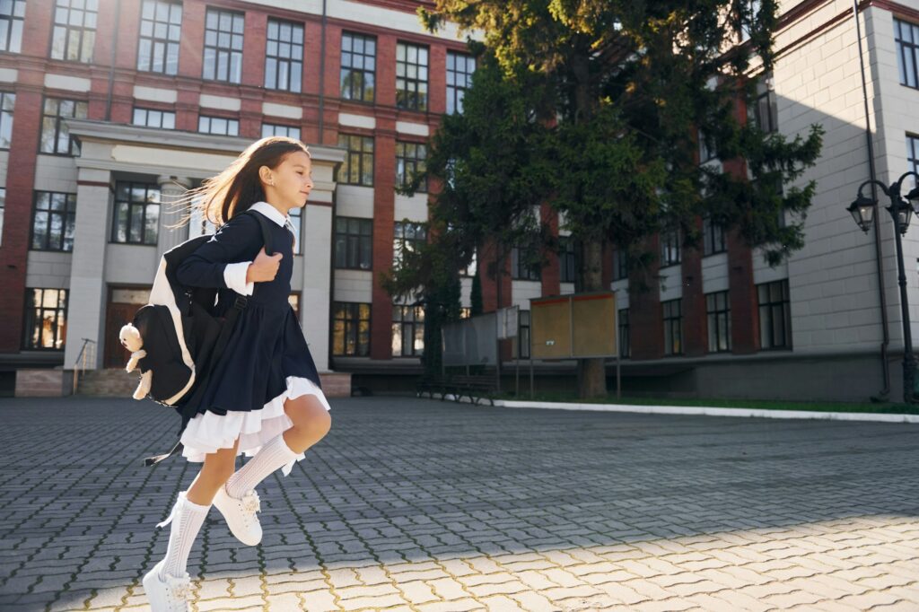 Having a walk. Schoolgirl is outside near school building